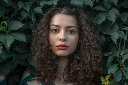 a woman posing for a photo with a leaves background