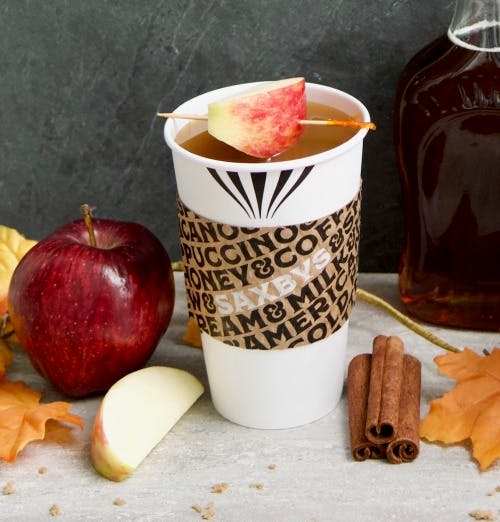 an apple next to a cup of coffee on a table