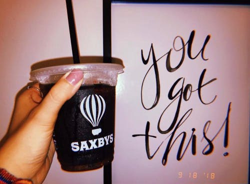 a person holding a cup of black coffee