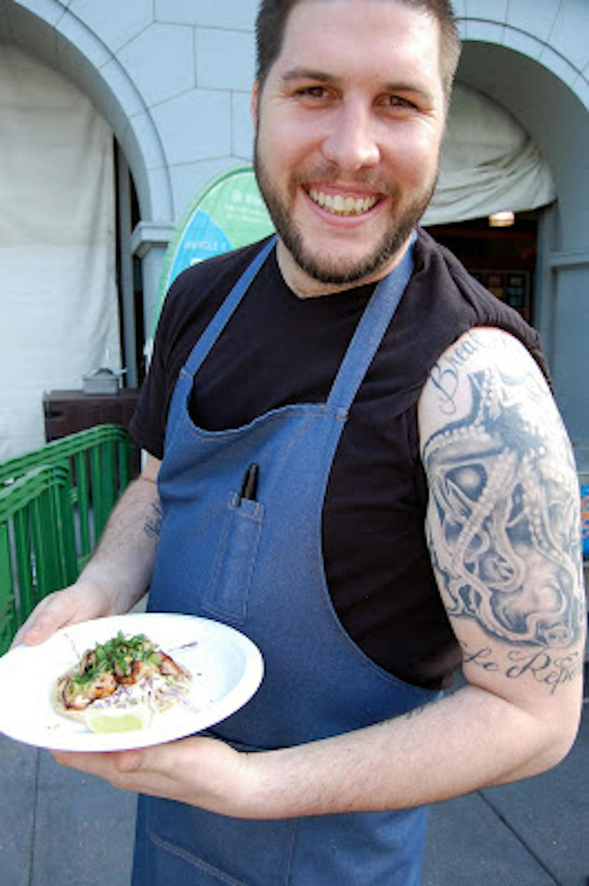 a man with tattoos posing with the fish taco