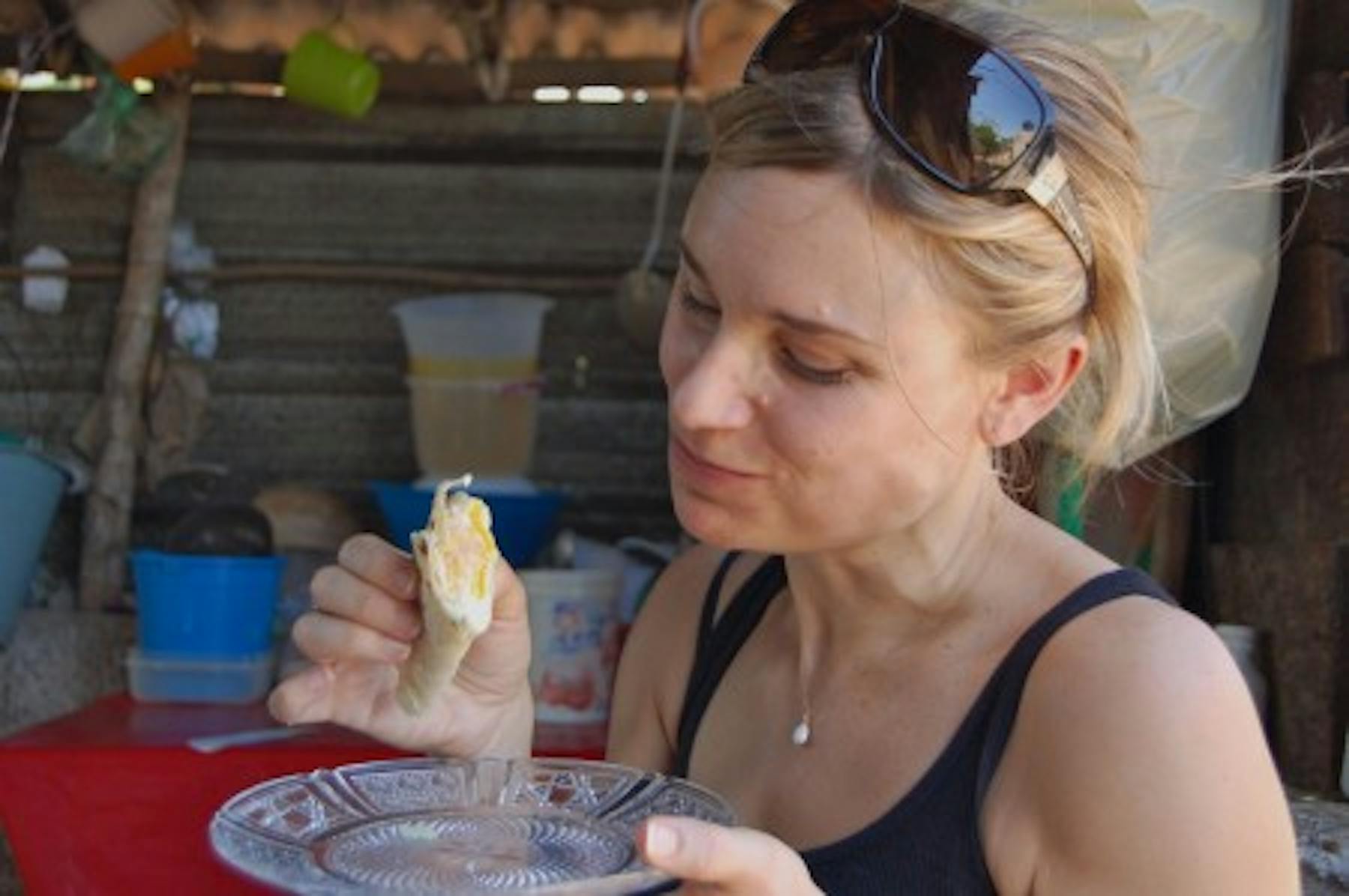 a blond woman eating gordita with an egg