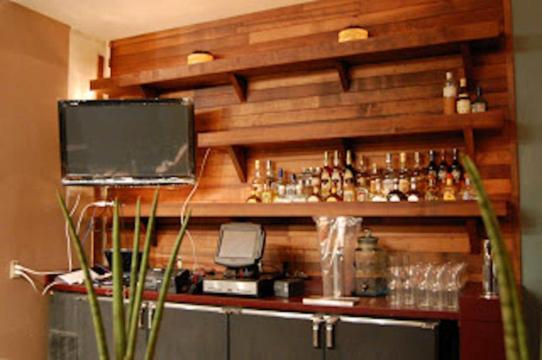 a front desk with a tv and bottles of alcohol