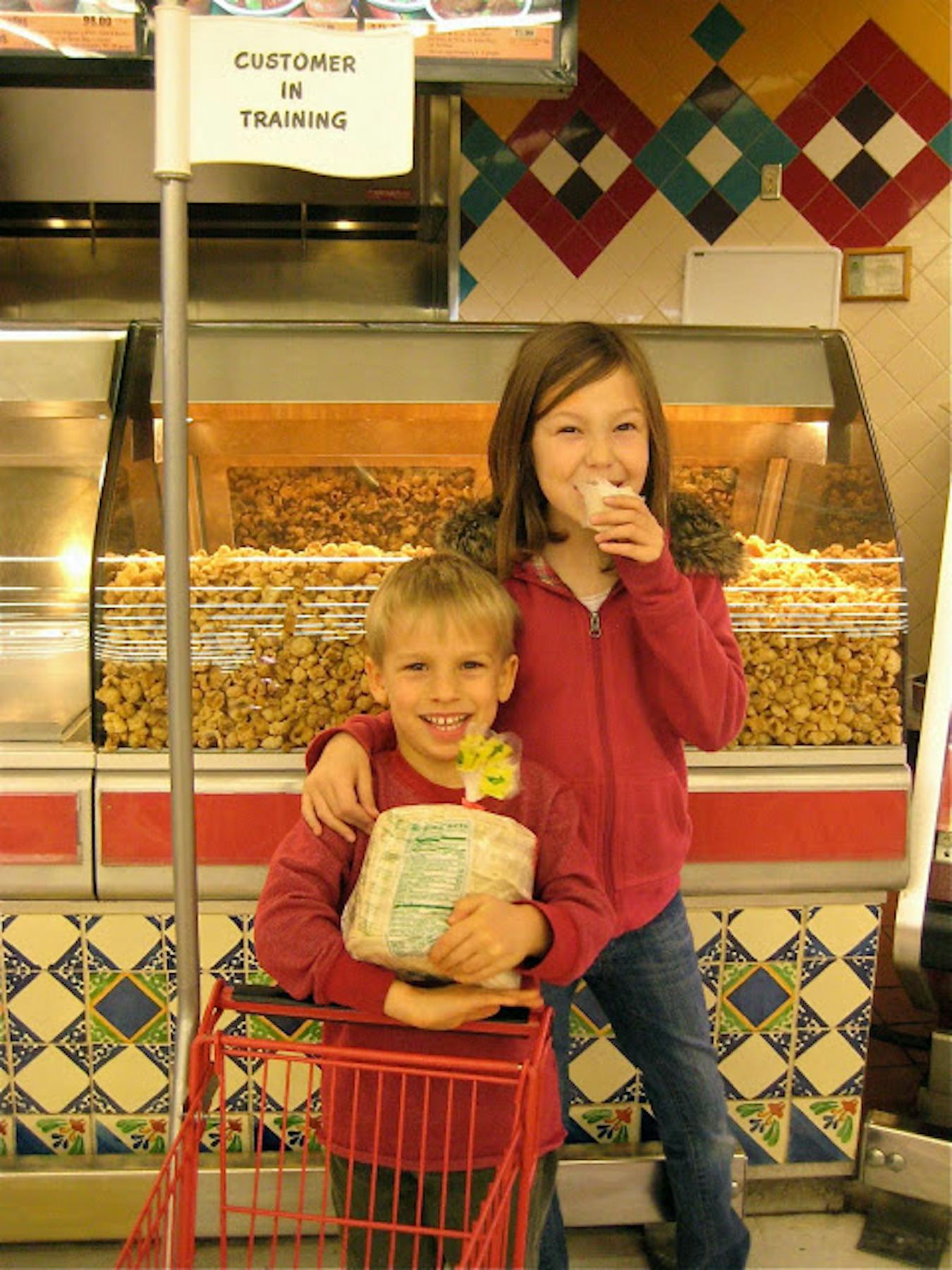 Moss and Mia eating a tortilla fresh off the press in front of a case of pork rinds.