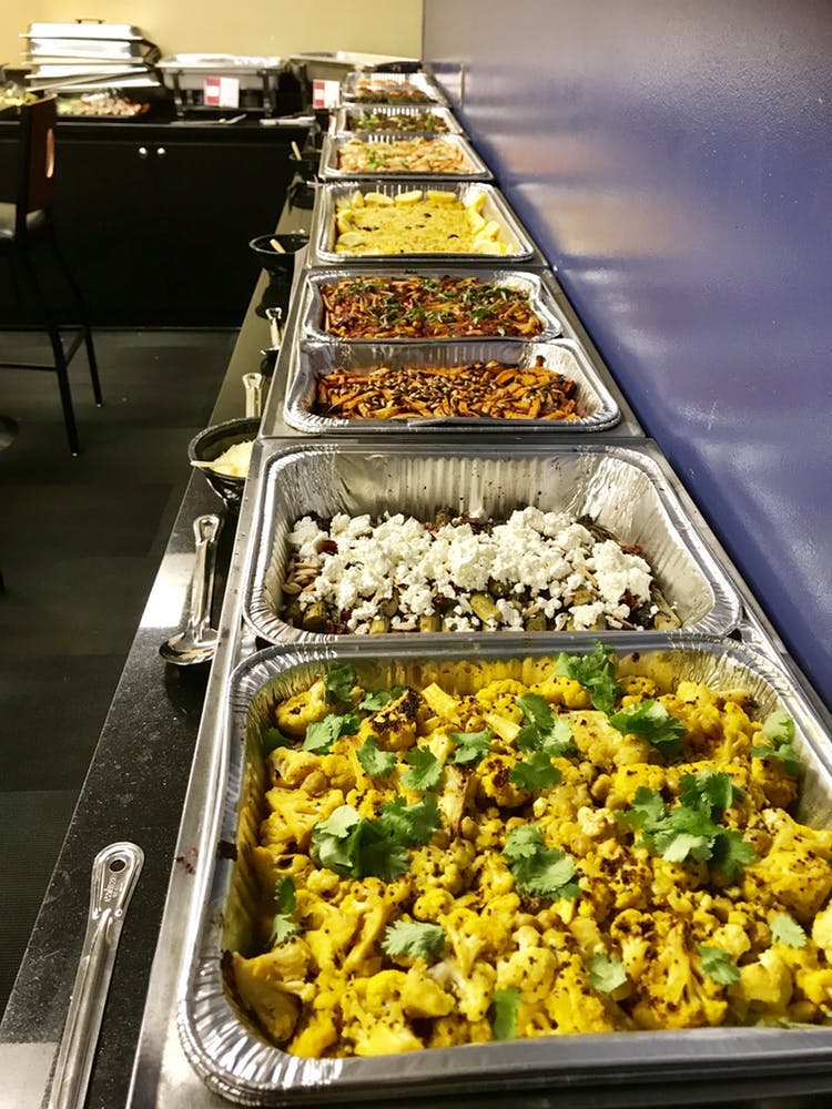 long buffet of food including curried cauliflower and other vegetables