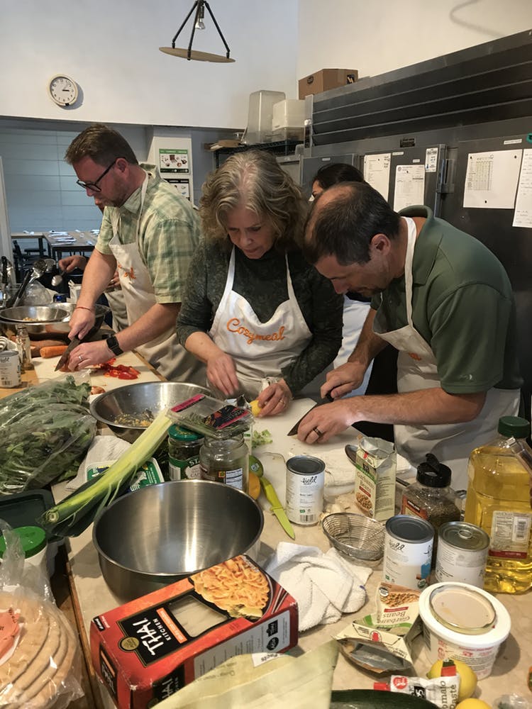 3 people in aprons cooking in a kitchen