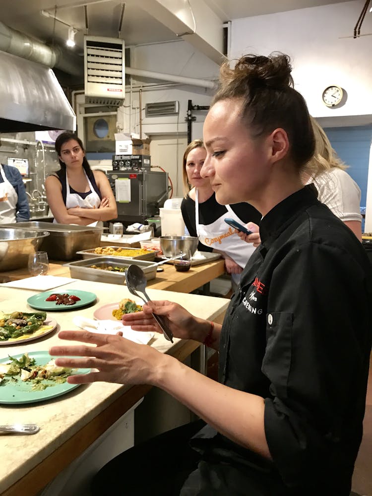 a woman in a black chefs coat tasting plates of food