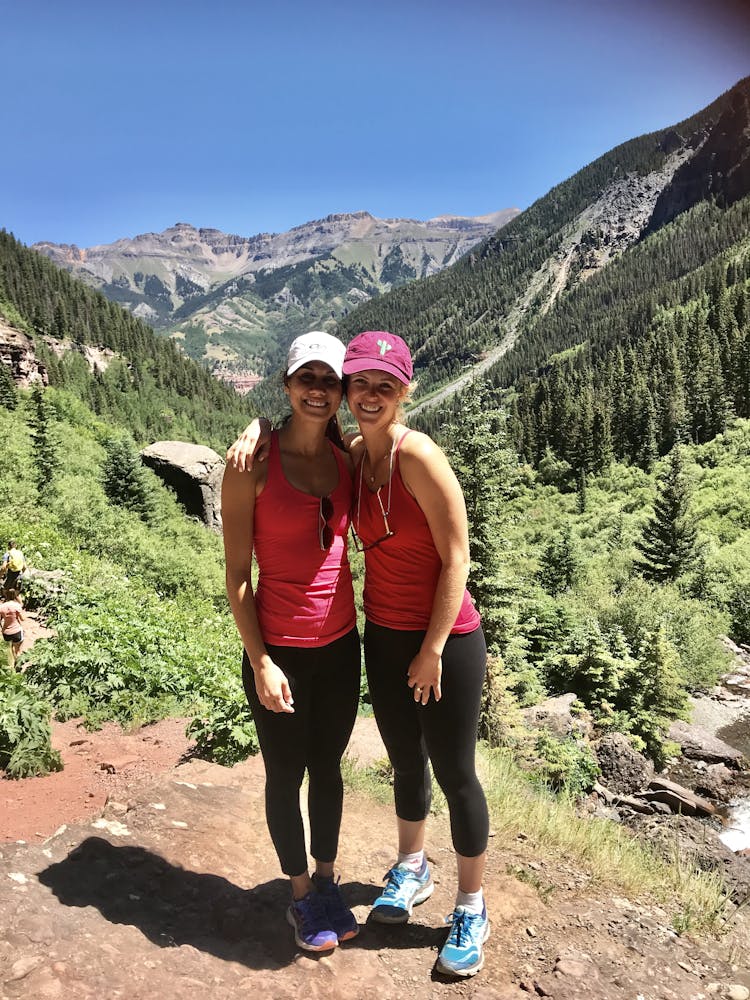two women smiling with mountains and trees behind them