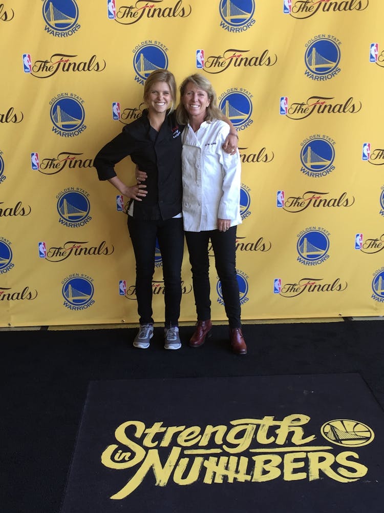 Two female chefs in front of the NBA Finals banner
