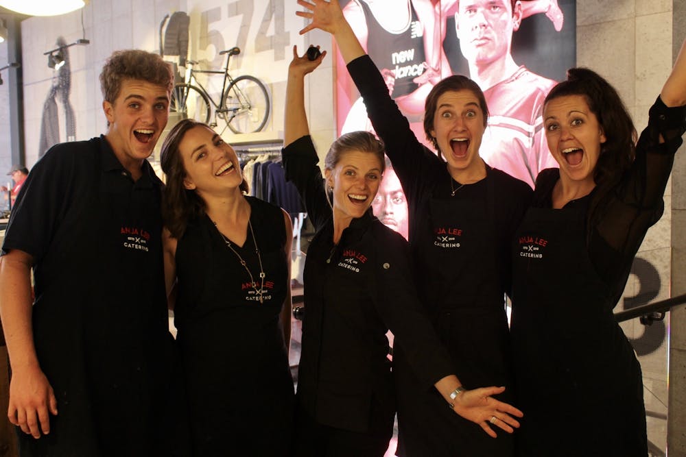 5 people in black aprons cheering