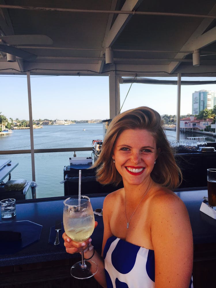 woman smiling next to the water holding a wine glass