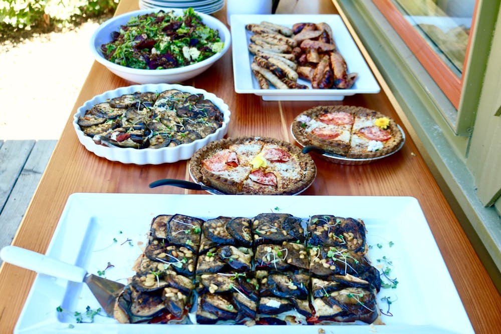 a buffet of food with quiches, salat, and eggplant