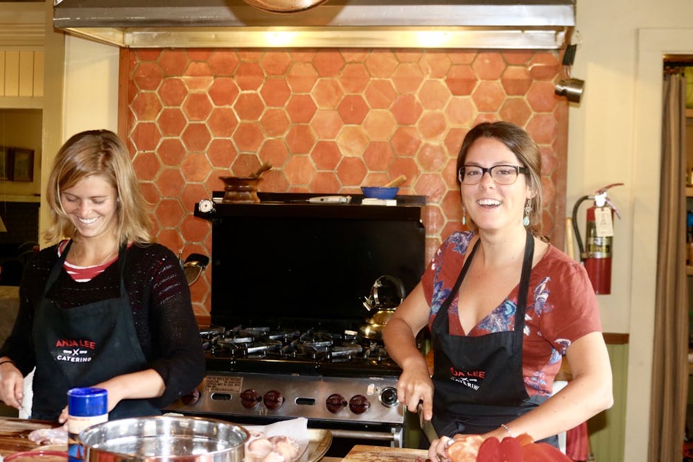 two women smiling and cooking