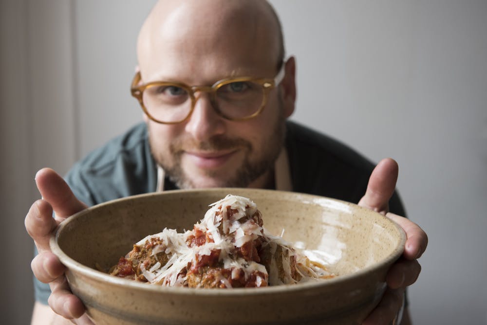 a man holding a plate of meatballs