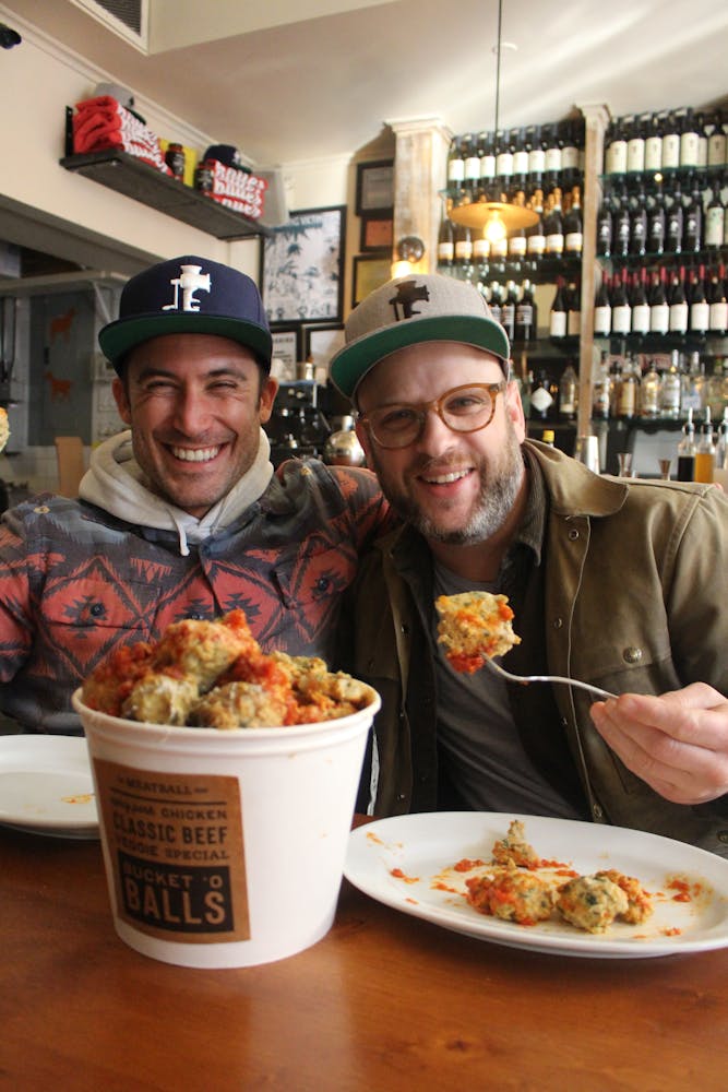 man smiling at the camera while eating meatballs