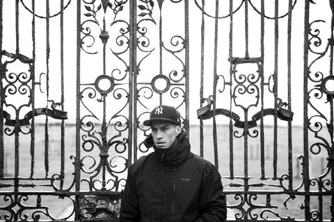 Black and white picture of young man standing in front of a gate